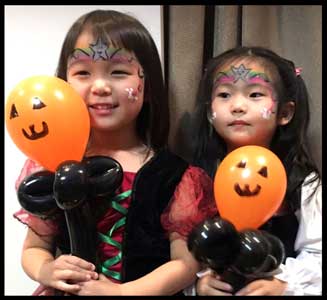 2 girls show off their halloween facepainting and twisted balloons at kids halloween party in New Jersey