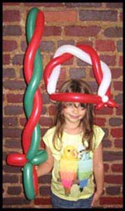 Girl wears a balloon twisted hat and brandishes a balloon sword at her Christmas party