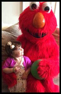 2 year old child is awed by Elmo character at her toddler birthday party in Long Island NY